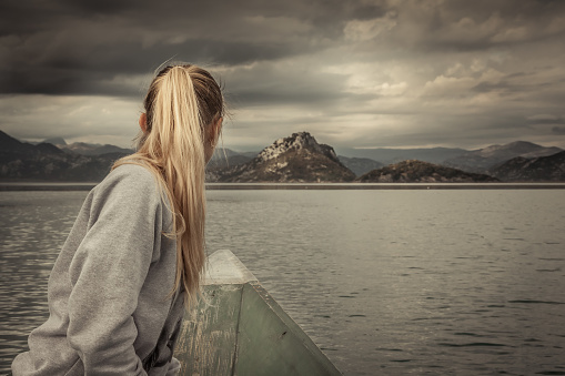 viajero-mujer-navegando-en-barco-hacia-tierra-con-paisaje-de-montañas-en-el-horizonte-en-un-día